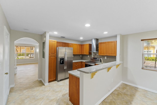 kitchen with wall chimney exhaust hood, stainless steel appliances, backsplash, kitchen peninsula, and a kitchen bar