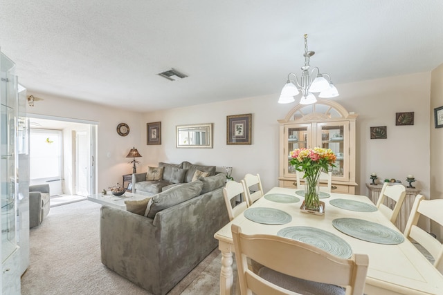 carpeted dining area with a chandelier and a textured ceiling