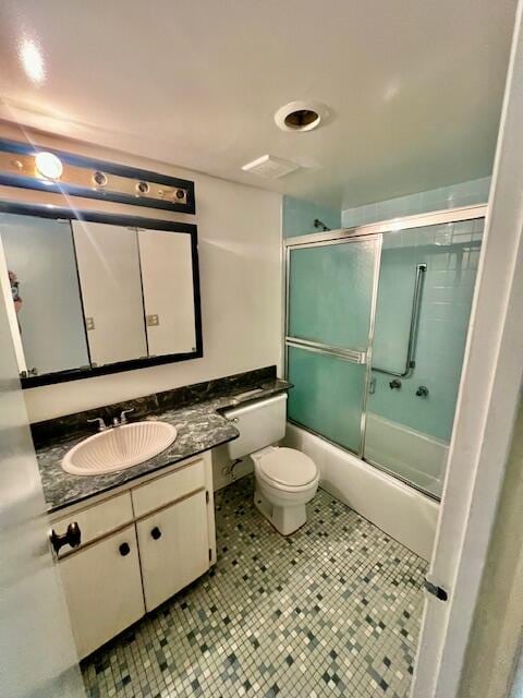 full bathroom featuring tile patterned floors, toilet, vanity, and combined bath / shower with glass door