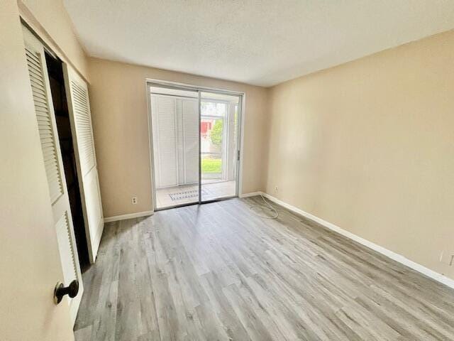 unfurnished room featuring light hardwood / wood-style floors and a textured ceiling