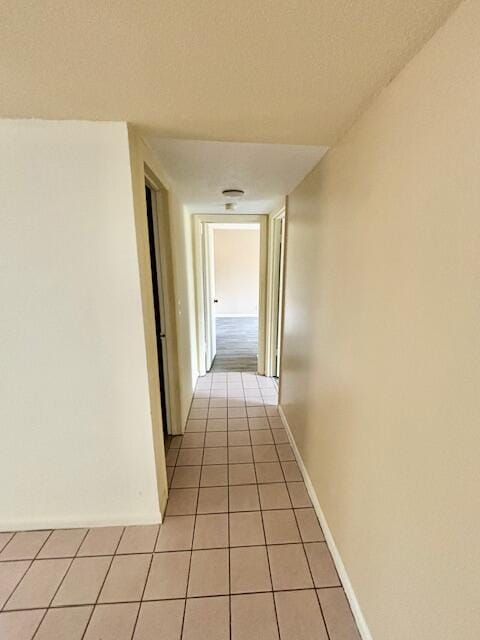 corridor with light tile patterned flooring and a textured ceiling