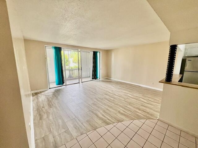 unfurnished living room with a textured ceiling and light hardwood / wood-style flooring