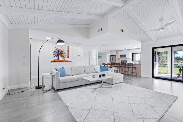 tiled living room featuring ceiling fan and vaulted ceiling with beams