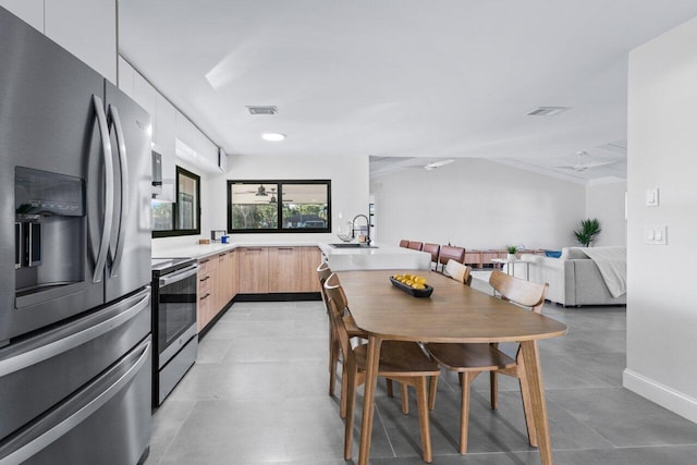 kitchen featuring stainless steel appliances, light brown cabinetry, white cabinetry, and sink