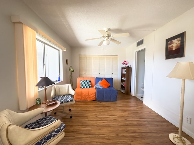 living area with hardwood / wood-style flooring, ceiling fan, and a textured ceiling