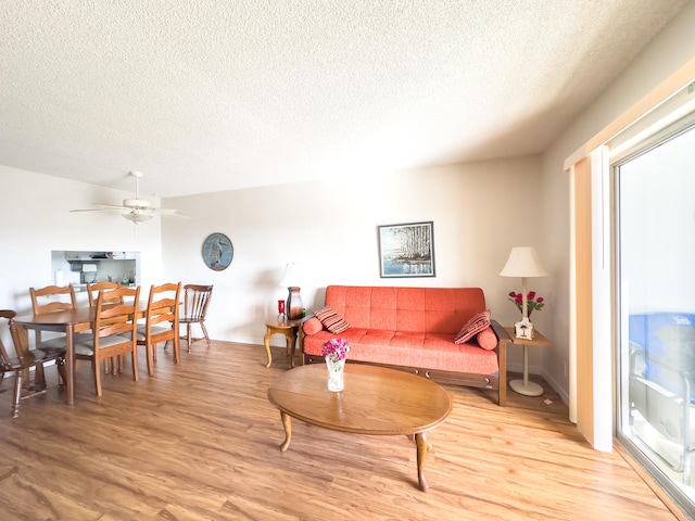 living room featuring a textured ceiling, light hardwood / wood-style floors, and ceiling fan