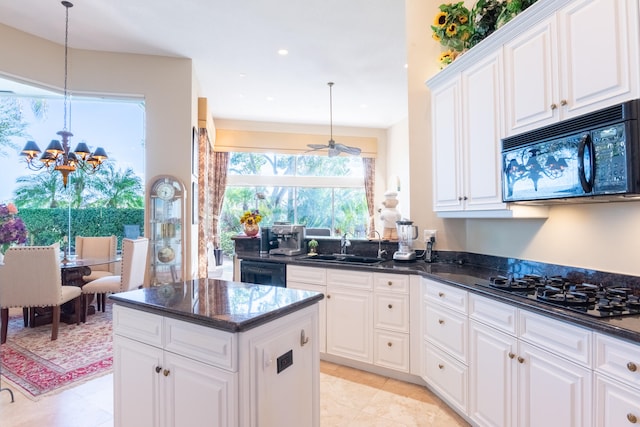 kitchen featuring pendant lighting, black appliances, ceiling fan with notable chandelier, white cabinets, and a kitchen island