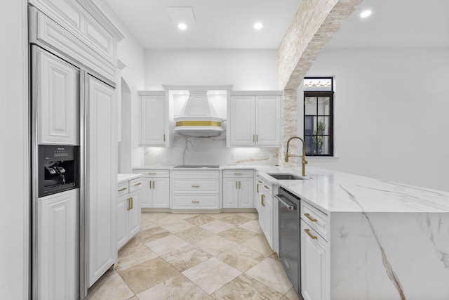 kitchen with a sink, paneled built in fridge, white cabinets, stainless steel dishwasher, and custom exhaust hood