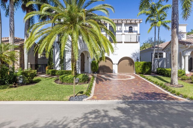 mediterranean / spanish home featuring a balcony and a front lawn