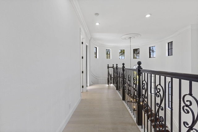 corridor featuring light wood-style floors, ornamental molding, and recessed lighting