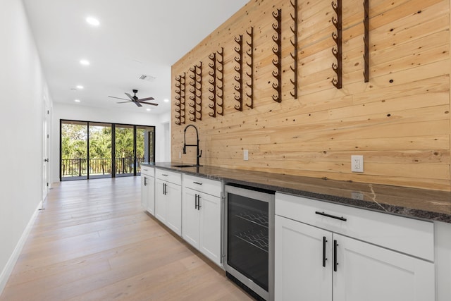 kitchen with wine cooler, light wood finished floors, visible vents, white cabinets, and a sink