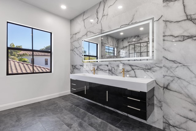 bathroom featuring double vanity, stone wall, and recessed lighting