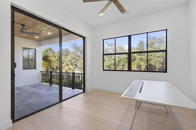 unfurnished room with ceiling fan, plenty of natural light, wood finished floors, and baseboards