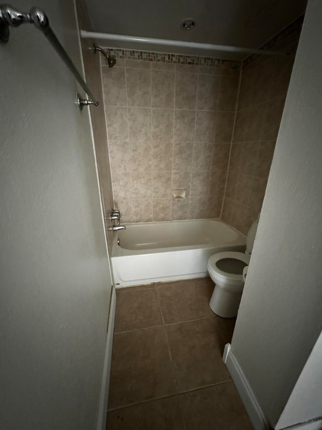 bathroom with tile patterned floors, tiled shower / bath combo, and toilet