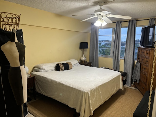 carpeted bedroom with ceiling fan and a textured ceiling