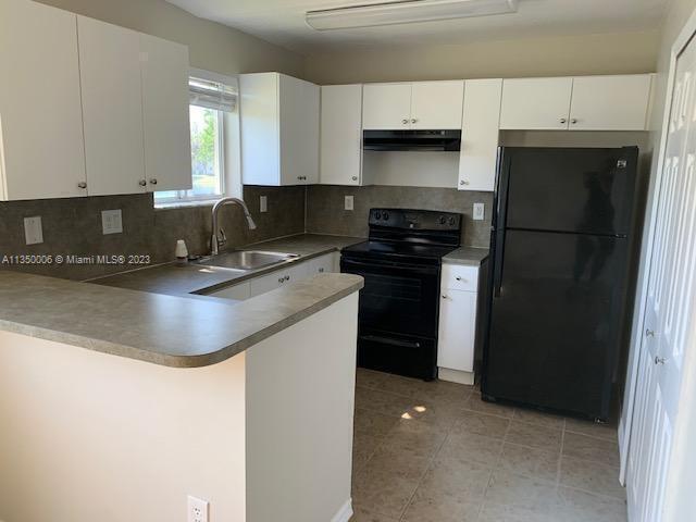 kitchen with black appliances, tasteful backsplash, sink, white cabinets, and kitchen peninsula