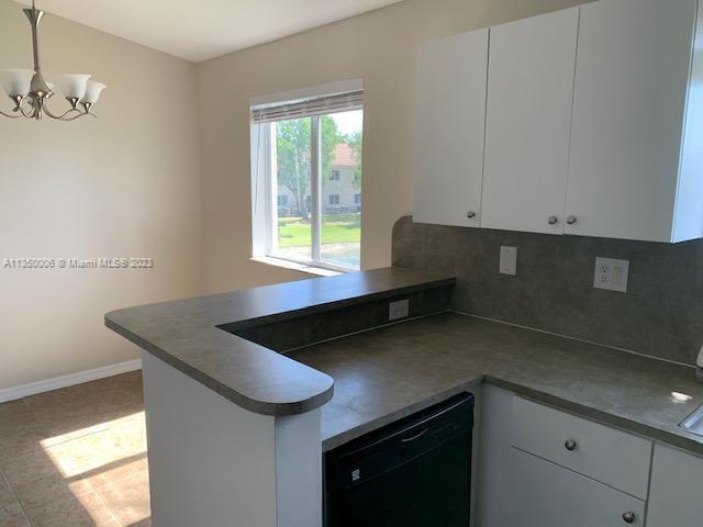 kitchen featuring kitchen peninsula, white cabinetry, decorative backsplash, and dishwasher