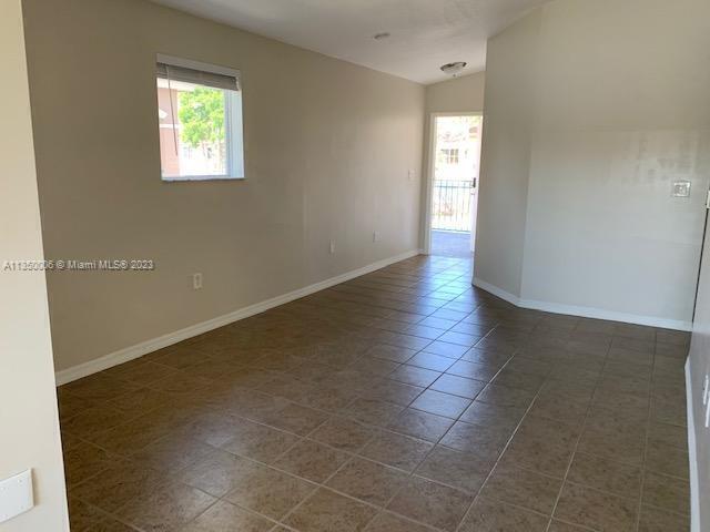 tiled spare room with lofted ceiling and a healthy amount of sunlight