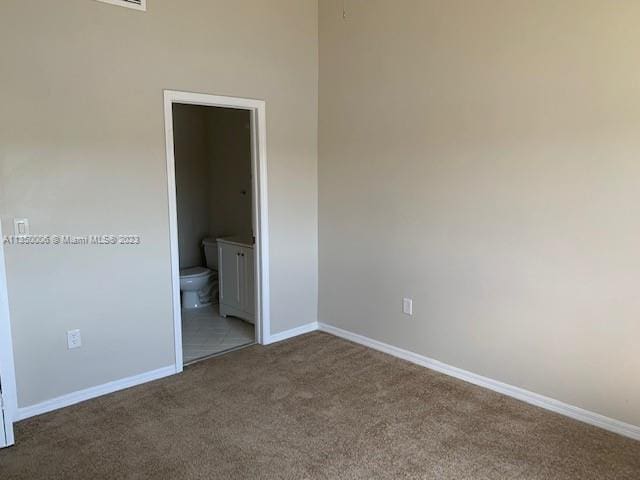 unfurnished bedroom featuring ensuite bath and carpet floors