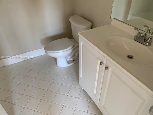 bathroom with toilet, vanity, and tile patterned flooring