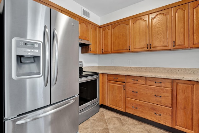 kitchen with light stone countertops, light tile patterned floors, and appliances with stainless steel finishes