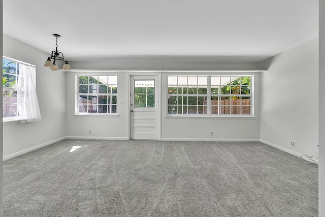 spare room featuring carpet and a chandelier