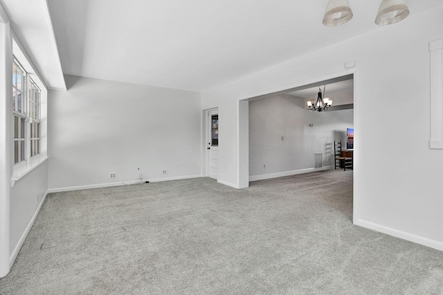 unfurnished living room featuring light carpet and a notable chandelier