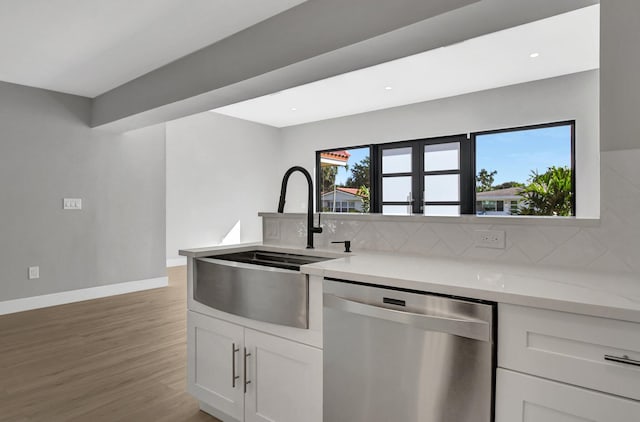 kitchen featuring hardwood / wood-style floors, white cabinetry, dishwasher, and tasteful backsplash