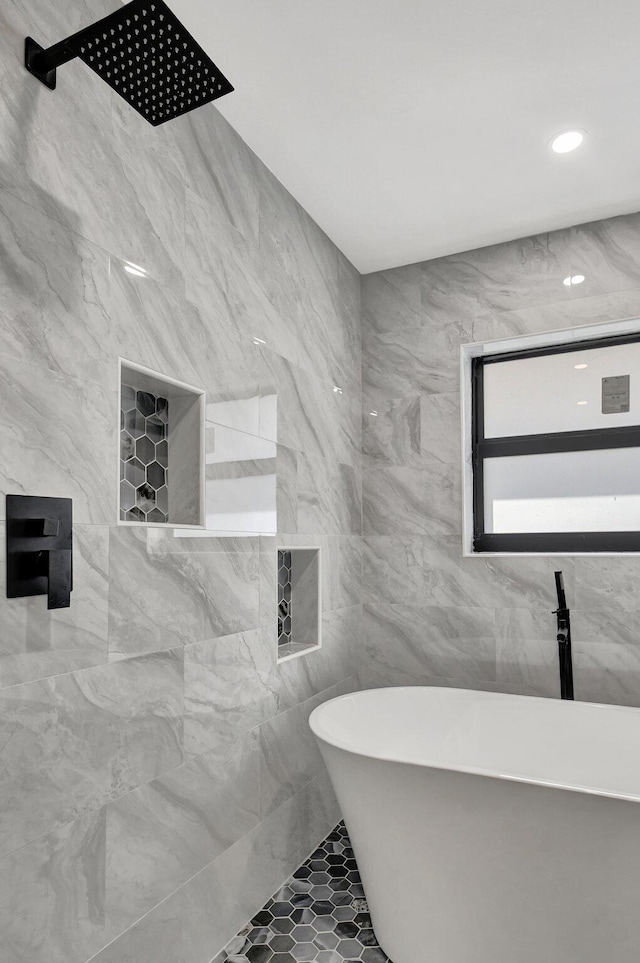 bathroom with a washtub, tile patterned floors, and tile walls