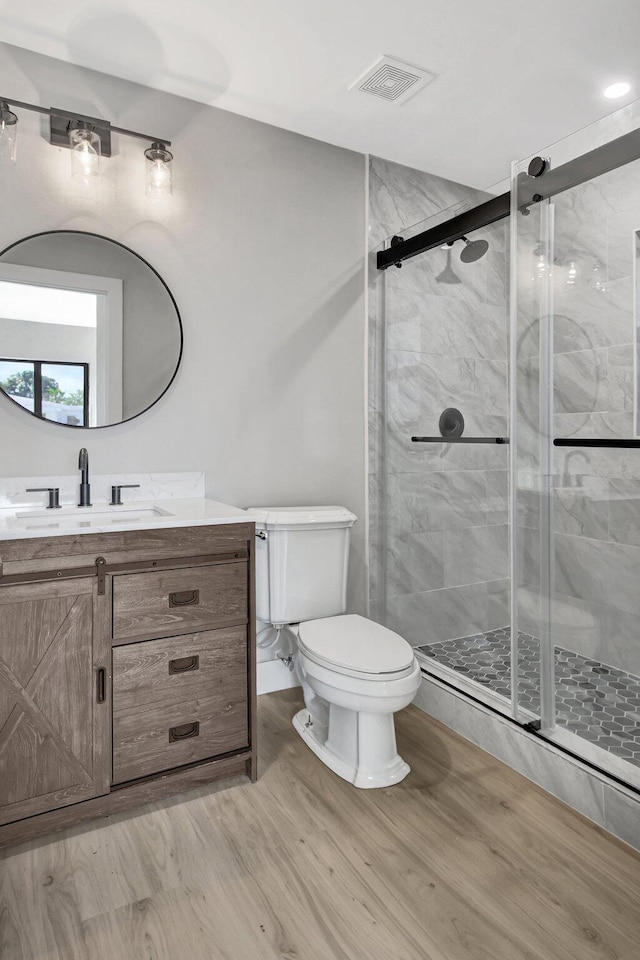 bathroom with hardwood / wood-style floors, an enclosed shower, vanity, and toilet