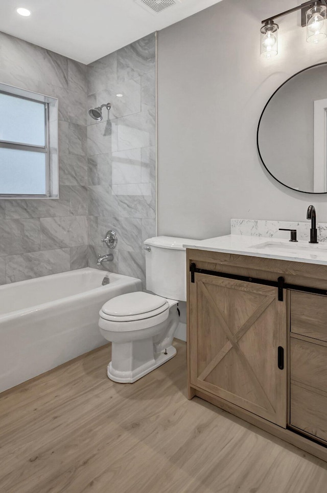 full bathroom featuring toilet, tiled shower / bath combo, vanity, and hardwood / wood-style floors