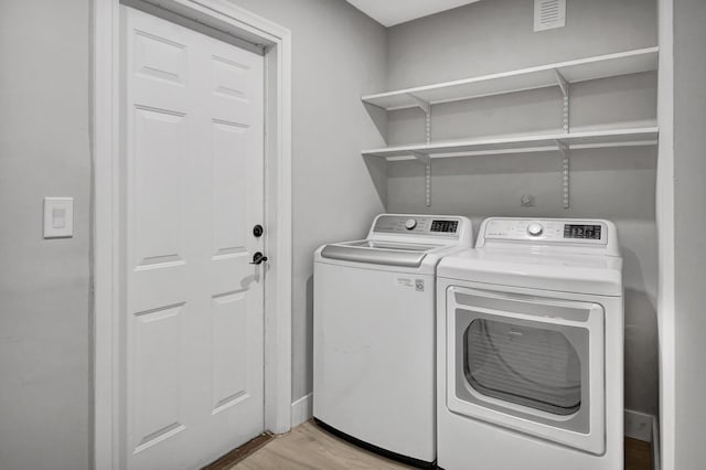 laundry area with washer and dryer and light wood-type flooring