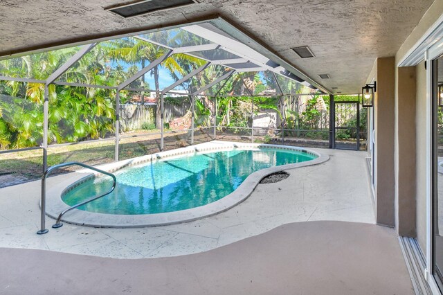 view of swimming pool featuring glass enclosure and a patio area