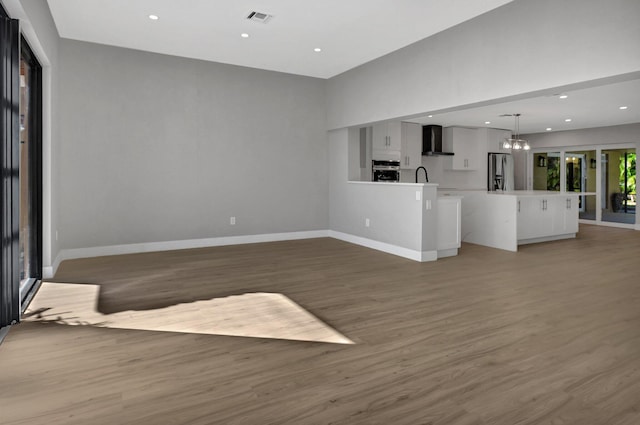 unfurnished living room with an inviting chandelier and dark hardwood / wood-style floors