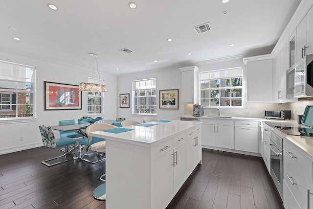 kitchen featuring dark hardwood / wood-style floors, white cabinetry, and hanging light fixtures