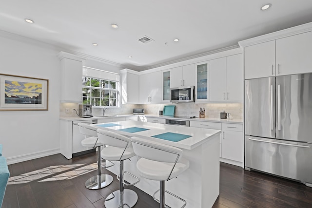 kitchen with white cabinetry, dark hardwood / wood-style flooring, a kitchen island, and appliances with stainless steel finishes