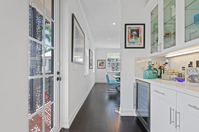 bar with dark wood-type flooring, beverage cooler, backsplash, crown molding, and white cabinets