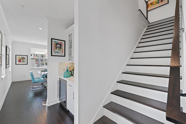 stairway with hardwood / wood-style floors, crown molding, wine cooler, and bar area