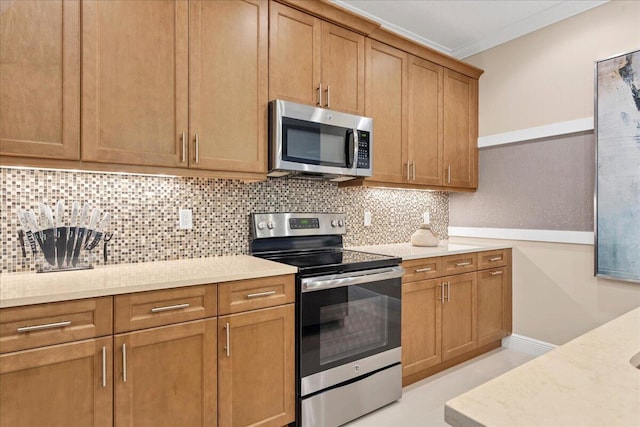 kitchen featuring light stone counters, brown cabinets, stainless steel appliances, crown molding, and backsplash