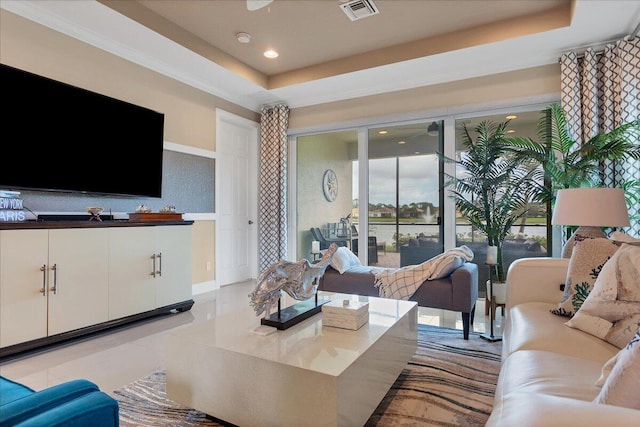 living area with a tray ceiling, recessed lighting, visible vents, and a healthy amount of sunlight