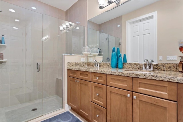 bathroom featuring double vanity, a sink, and a shower stall