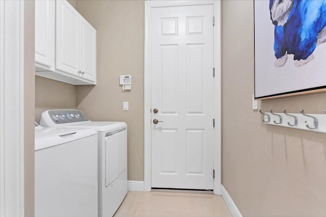 laundry room featuring light tile patterned floors, washing machine and clothes dryer, cabinet space, and baseboards