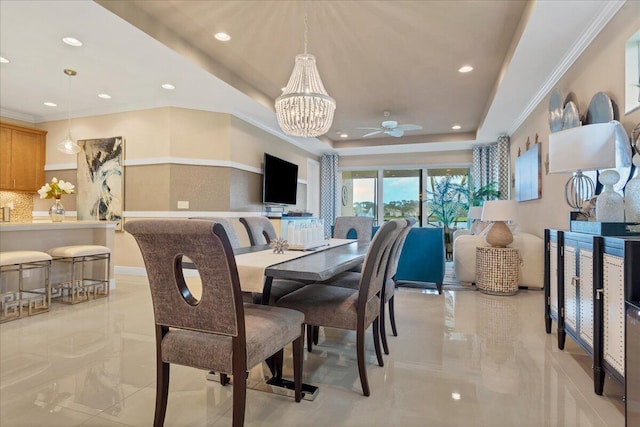 dining space with a tray ceiling, marble finish floor, recessed lighting, ornamental molding, and ceiling fan with notable chandelier