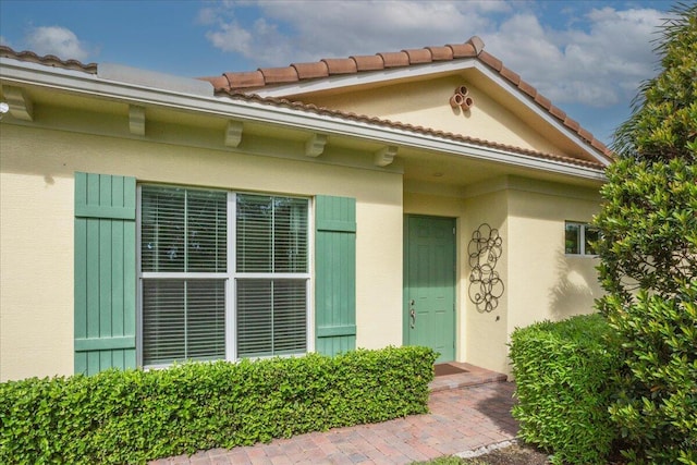 doorway to property with a tiled roof and stucco siding