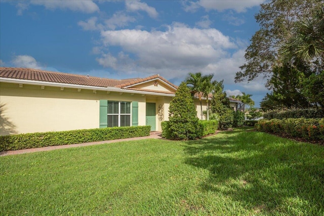 exterior space featuring a front yard, a tiled roof, and stucco siding