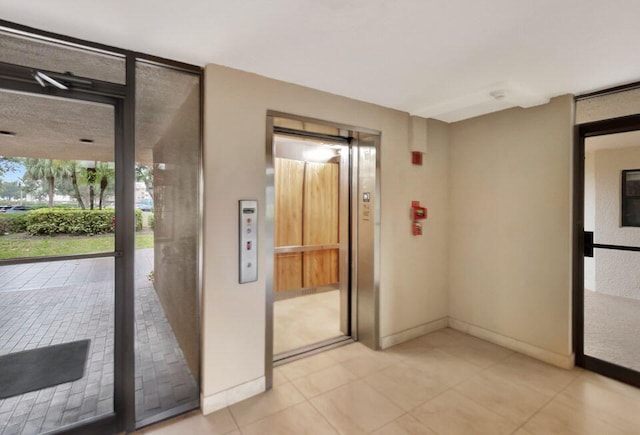 interior space with a wall of windows, elevator, and light tile patterned floors