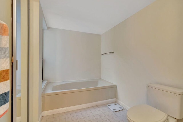 bathroom featuring tile patterned floors, toilet, and a tub to relax in