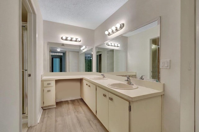 bathroom with hardwood / wood-style flooring, vanity, and a textured ceiling