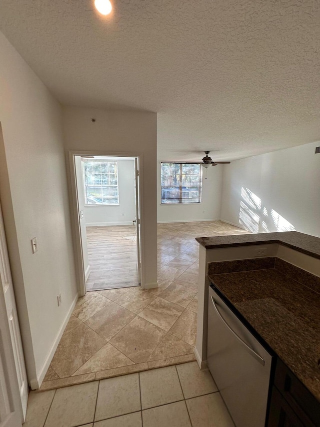 hallway with a textured ceiling, light tile patterned floors, and a healthy amount of sunlight