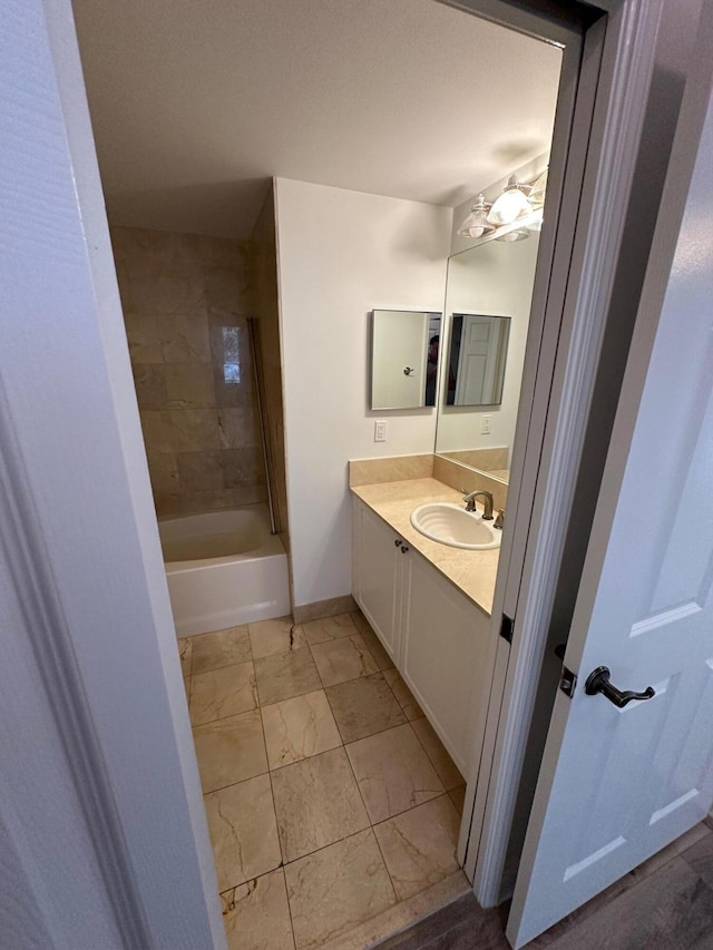 bathroom featuring tiled shower / bath combo and vanity